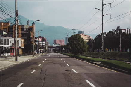 Calle vacía en una ciudad de América Latina con edificios modernos y montañas al fondo, representando desafíos de infraestructura y desarrollo territorial